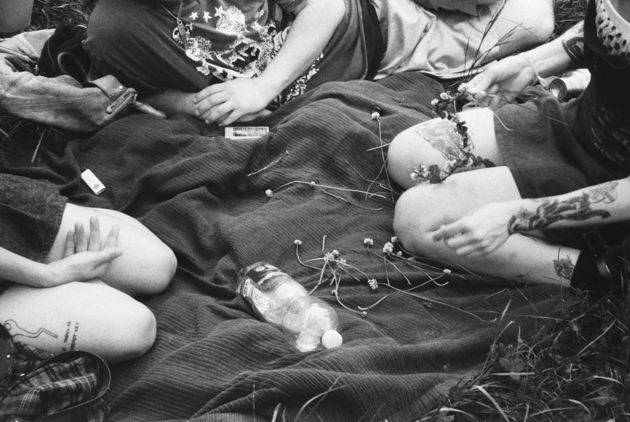 Audience members sitting on a blanket, captured in black and white.