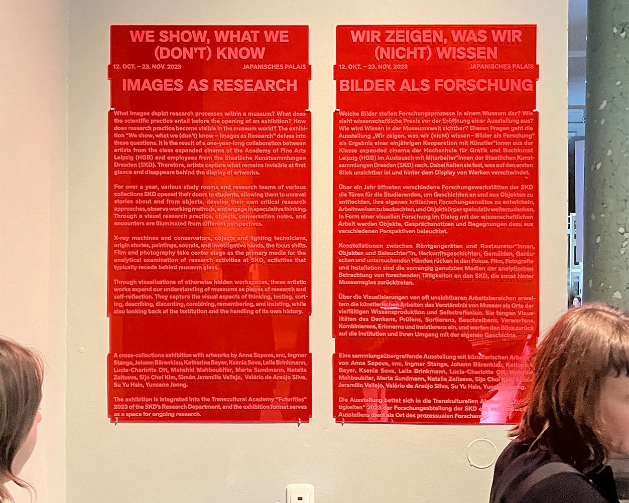 Exhibition signage featuring engraved text on bright red acrylic glass